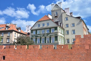 Varşova 'nın eski kasabasındaki tuğla bir duvarın arkasındaki tarihi evler.