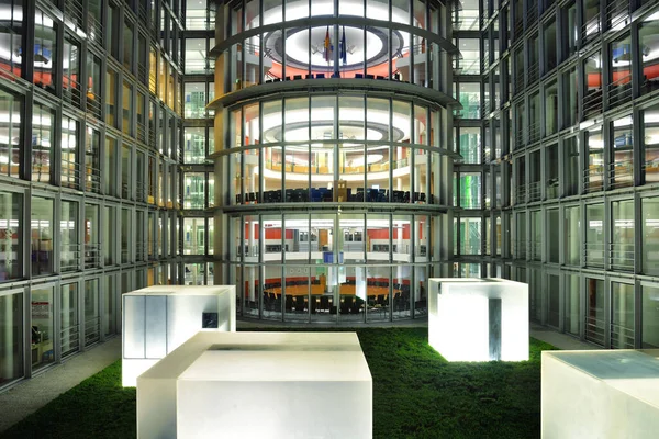 Akşam saatlerinde modern bir kamu binasının aydınlatılmış cam cephesi