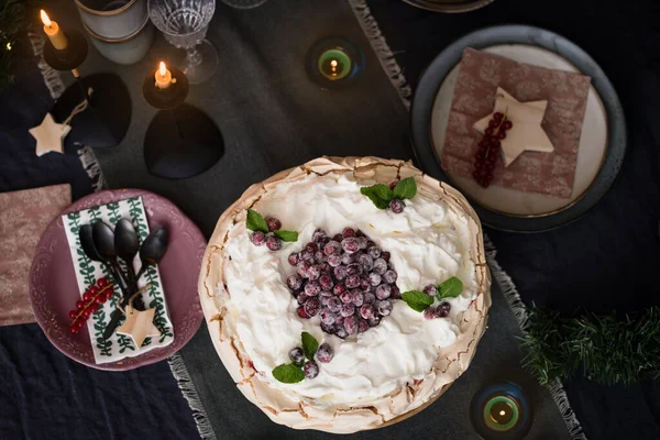 Christmas cake Pavlova with cranberries decorated with on dark blue background