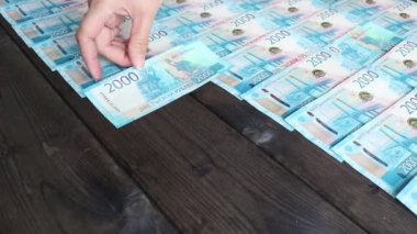 Kadınların elleri 2000 rublelik Rus banknotlarını koyu renkli bir masanın üzerine seriyor. Para arkaplanı.
