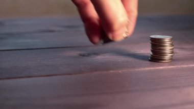 Kadın eli madeni para sütunları koyuyor, yığınla para çöküyor. Döviz kurunun büyümesi ve düşmesi kavramı. Paranın kıymetini bilmek ve değer kaybetmek. Seçici odak