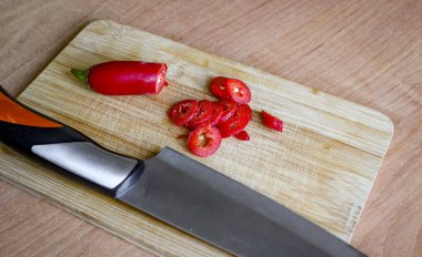 Kırmızı kırmızı kırmızı biber ahşap bir kesme tahtasının üzerinde dilimlenir. Durgun hayat. Et için çok baharatlı bir baharat..