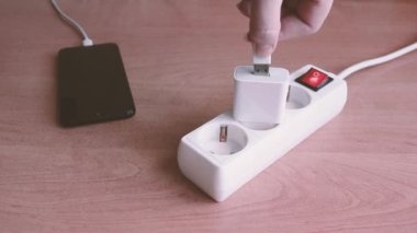 Bir kadının eli USB kablosunu akıllı telefonu şarj etmek için USB portuna takar ve USB kablosunu çıkarır..