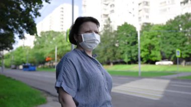 Şehrin sokaklarında maske takan bir kadın. Statik kameralı bir video.