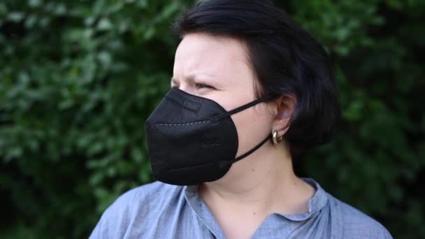 La mujer con una máscara médica negra levanta la cabeza, mira hacia arriba. Respirador negro. Vídeo de concepto pandémico 4k — Vídeo de stock