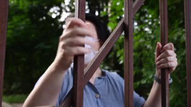 Çitin arkasında tıbbi maske takan bir kadın. Salgın sırasında izolasyon kavramı. Video.