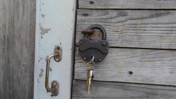 Porte-clés dans un cadenas antique à côté de la porte. caméra statique. — Video