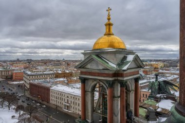 St. Isaac Katedrali 'nin çatısından gün boyunca bulutlu bir gökyüzüne karşı St. Petersburg' un (Rusya) karla kaplı sokaklarının manzarası. Yakınımızda altın kubbesi ve melek heykeli olan bir kule var.
