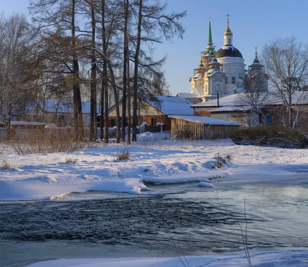 古い多ドーム教会と雪の中で激しく流れる川と冬の田園風景 背の高い木や茂み 田舎の家や青い空が風景を飾ります 村Byngi ウラル ロシア — ストック写真