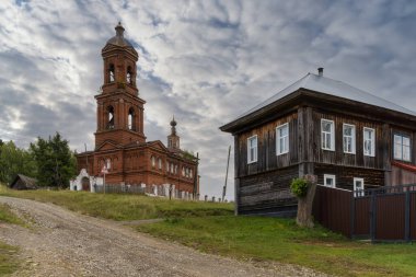 Güneşli bir yaz gününde (Kuzey Ural, Rusya) Vilgort köyünde yüksek bir tepede çan kulesi olan eski bir tuğla kilisenin manzarası. Harika tarihi mimari. Ahşap evlerin etrafında 