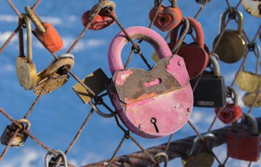 Soğuk bir kış gününde demir renkli kilitler parktaki parmaklıklara bağlandı. Donmuş metal kilitler. Yeni evliler için düğün günü geleneği. Kırılmaz aşkın ve birlikte mutlu bir hayatın sembolü. 