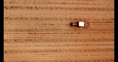 Beyaz ve kırmızı traktörün üzüm bağlarını sürdüğü drone görüntüsü