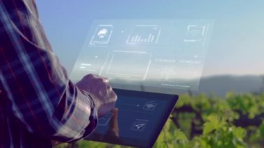 Farmer with tablet in vineyard field seeing technological advances and communication on digital screen