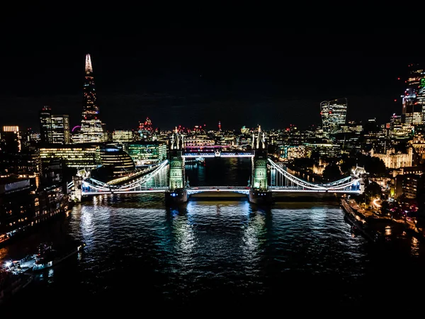伦敦塔桥在夜晚与城市建筑空中无人机的观点。伦敦最有名的桥梁之一和英国必看的地标 — 图库照片