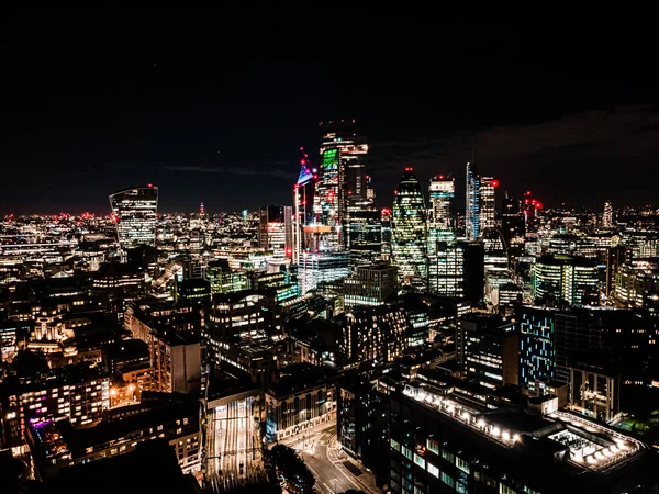 City of London een van de toonaangevende centra van de wereldwijde financiën in de nacht. Luchtfoto boven de grote stad 's nachts — Stockfoto