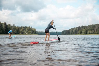 Paddling on a SUP board on a lake at sunny day. Stand up paddle boarding - awesome active outdoor recreation.