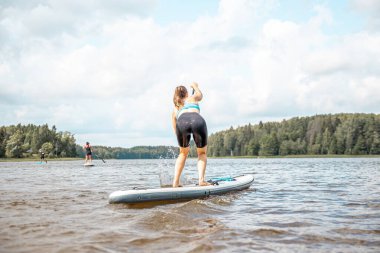 Paddling on a SUP board on a lake at sunny day. Stand up paddle boarding - awesome active outdoor recreation.