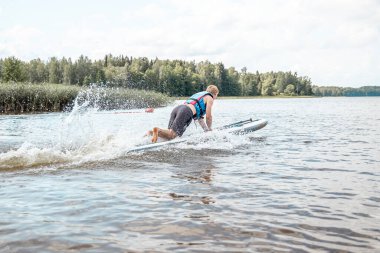 Paddling on a SUP board on a lake at sunny day. Stand up paddle boarding - awesome active outdoor recreation.