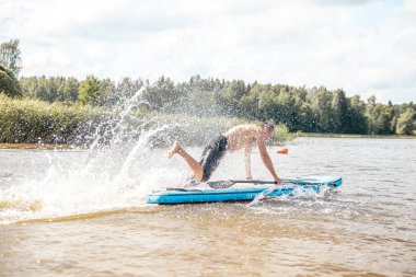 Paddling on a SUP board on a lake at sunny day. Stand up paddle boarding - awesome active outdoor recreation.