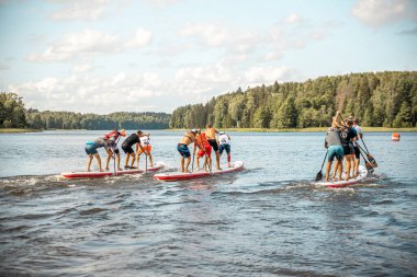Paddling on a SUP board on a lake at sunny day. Stand up paddle boarding - awesome active outdoor recreation.