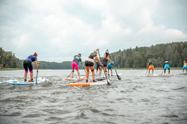 Vaidava, Latvia - 01.08.2021: A lot of People paddle with SUP stand up paddle board. SUP competition, race. awesome active outdoor recreation.