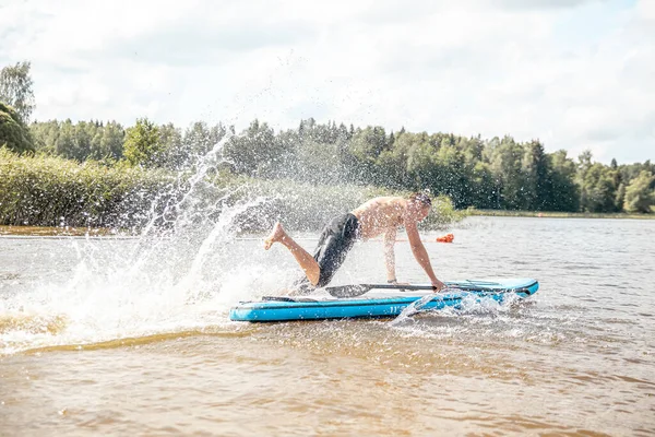 Paddling on a SUP board on a lake at sunny day. Stand up paddle boarding - awesome active outdoor recreation.