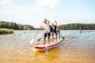 Vaidava, Latvia - 01.08.2021: A lot of People paddle with SUP stand up paddle board. SUP competition, race. awesome active outdoor recreation.
