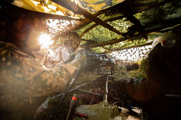 Close-up soldiers firing a 50 Cal Machine gun with spent brass around it. Military training, army war concept