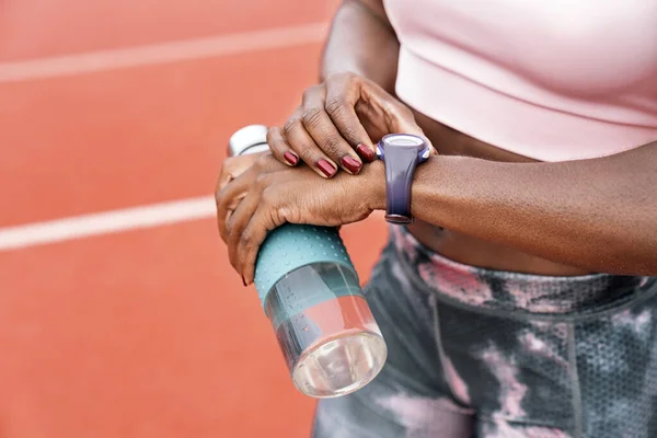 Atleta sprinter viendo el reloj con una botella de agua — Foto de Stock