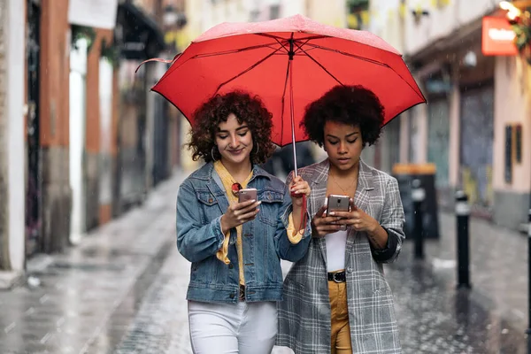 Amigos felices usando el teléfono en la calle —  Fotos de Stock