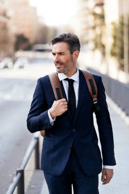 Şehirde yürüyen yakışıklı bir iş adamı.