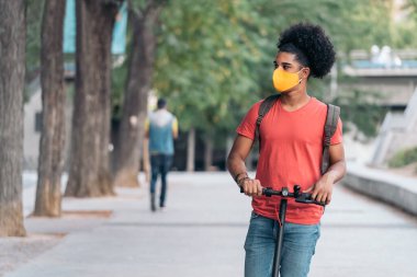 Elektrikli scooter 'ı olan genç Afrikalı Amerikalı.
