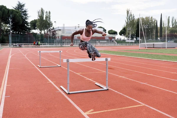 Atleta afroamericano velocista saltando un obstáculo — Foto de Stock