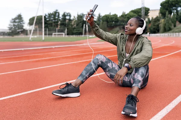 Atleta sprinter sentado escuchando música — Foto de Stock