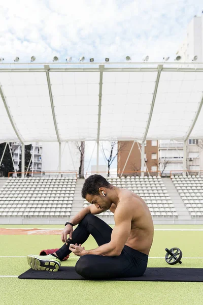 Vista lateral de un atleta usando el teléfono en pista atlética — Foto de Stock