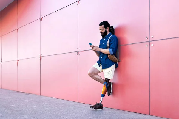 ชายที่มีขาเทียมยืนกับสมาร์ทโฟนในเมือง — ภาพถ่ายสต็อก