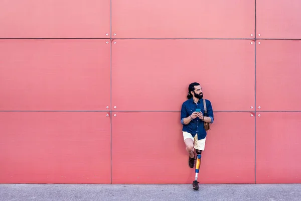 Pria dengan kaki buatan berdiri dengan smartphone di kota — Stok Foto