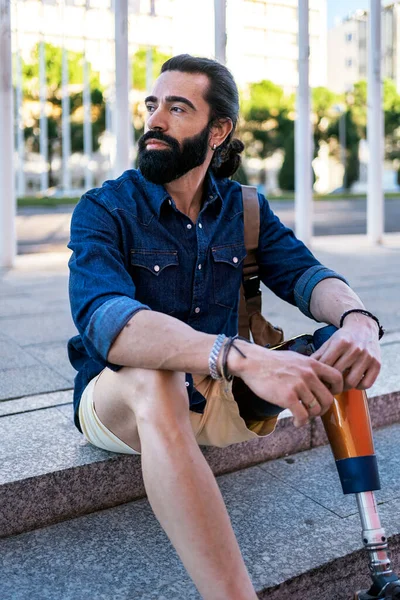 Pria dengan kaki bionik duduk di jalan — Stok Foto