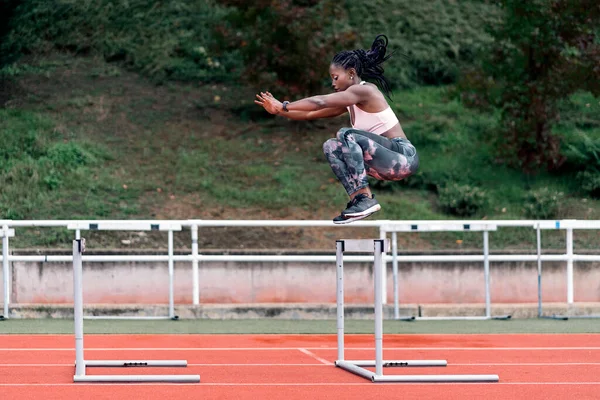 Atleta afroamericano velocista saltando un obstáculo — Foto de Stock