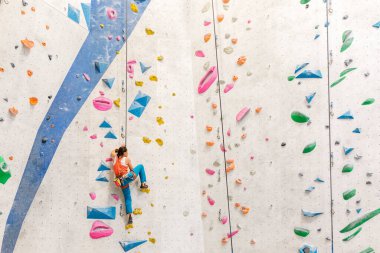 Genç kadın kaya tırmanışı yapıyor..