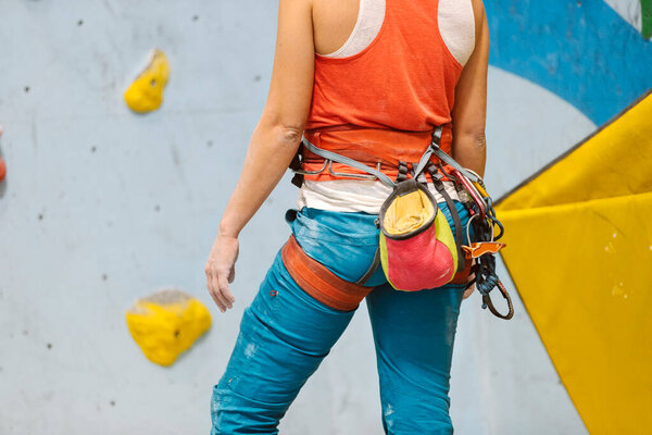 Woman getting ready for rock climb indoors.