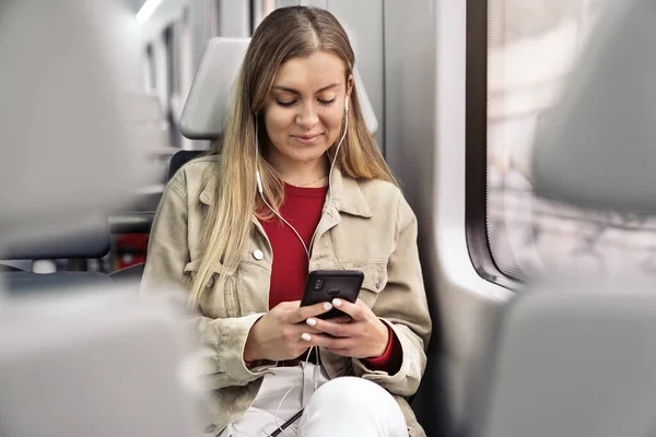 Chica rubia en tren con teléfono móvil — Foto de Stock
