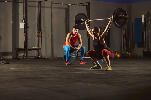 Woman squatting and lifting a barbell. — Foto de Stock