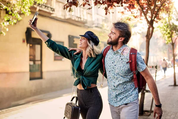 Couple walking on street taking a selfie — Fotografia de Stock