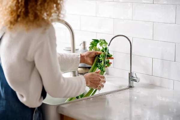 Woman cleaning vegetables in kitchen. — Foto de Stock