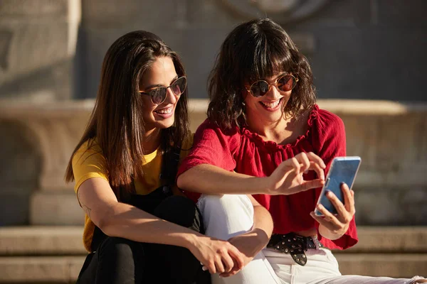 Duas meninas adolescentes sentadas e olhando para o smartphone. — Fotografia de Stock