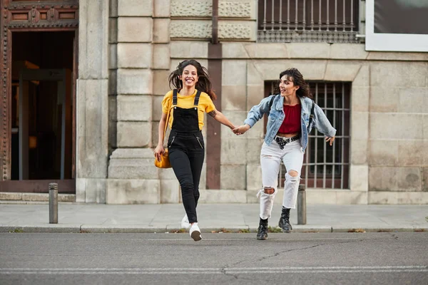 Two teenager girls running down street. — Zdjęcie stockowe
