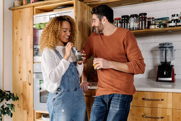 Couple laughing and standing in kitchen.