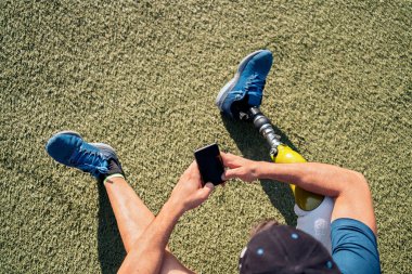 Engelli atlet telefon kullanarak oturuyor