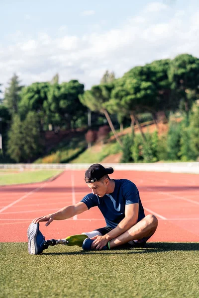 Atleta hombre discapacitado estiramiento con prótesis de pierna . — Foto de Stock